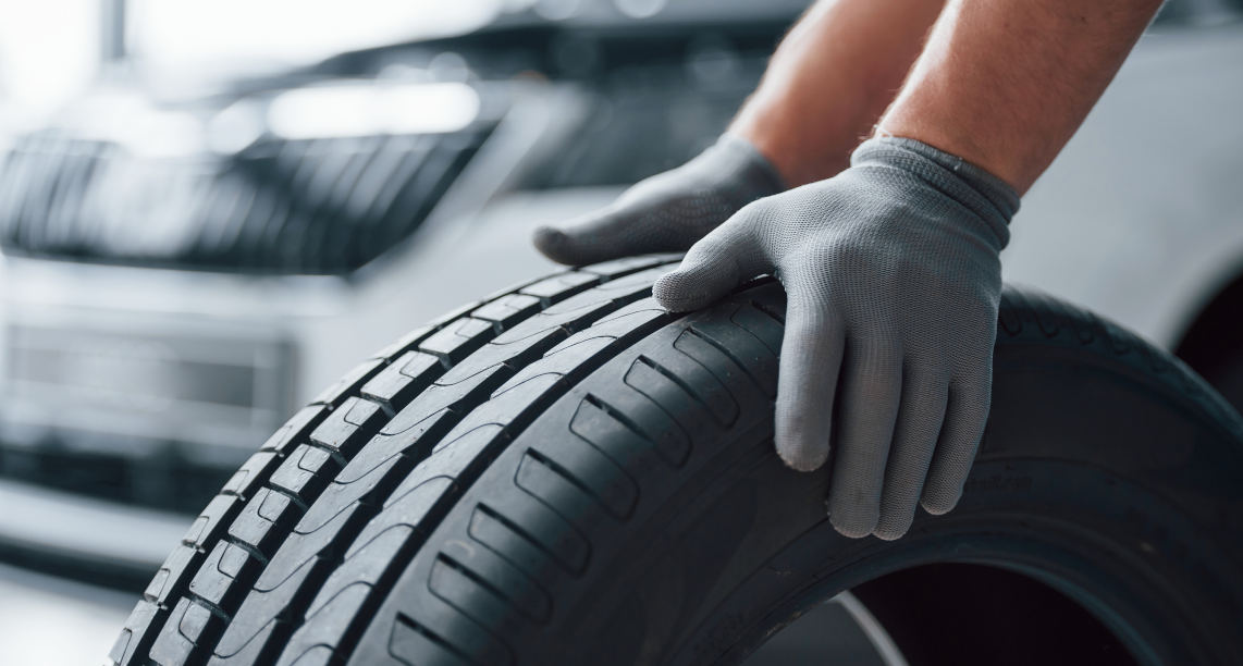 Hands only. Mechanic holding a tire at the repair garage. Replacement of winter and summer tires